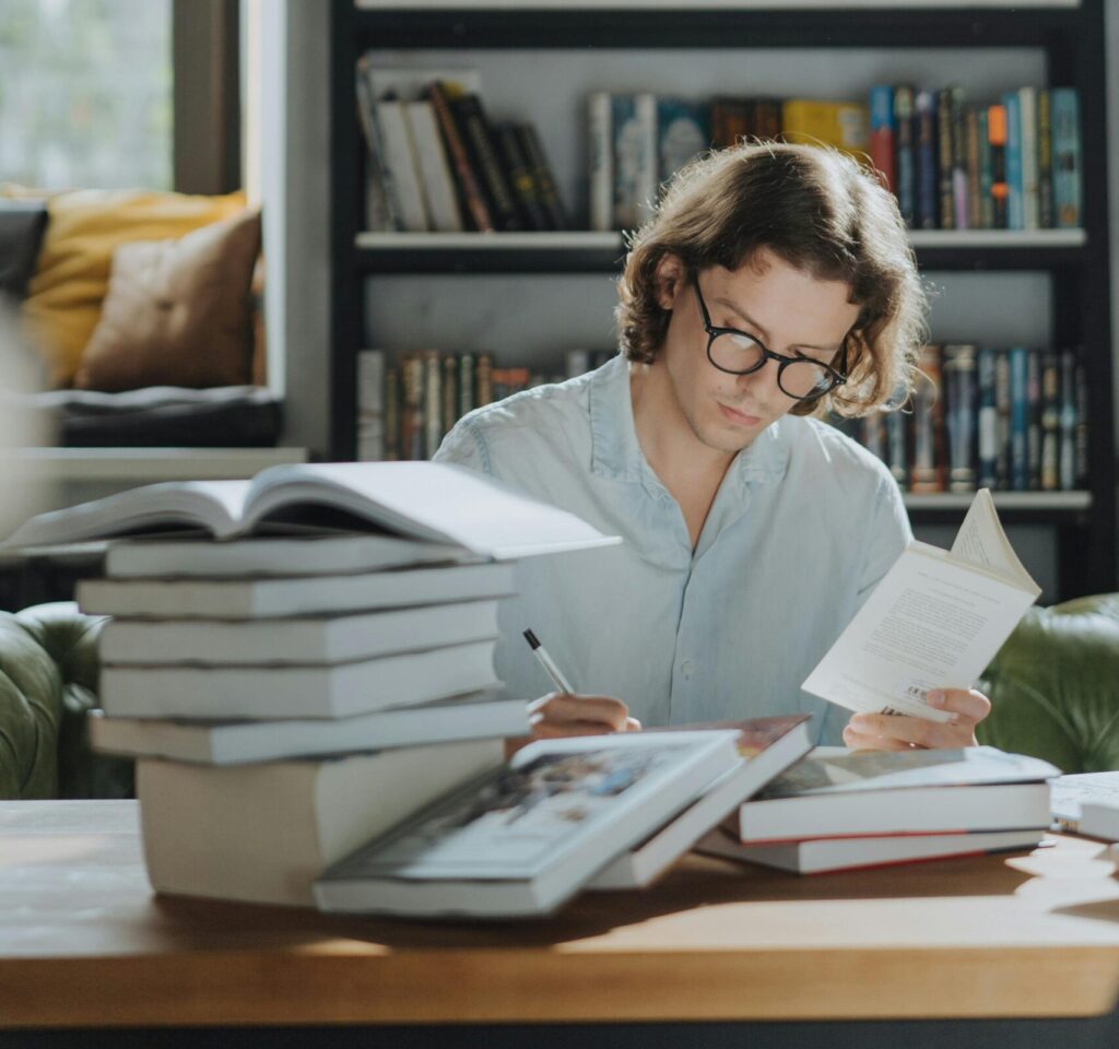 A young man focuses on studying amidst a bookstore environment, surrounded by books.